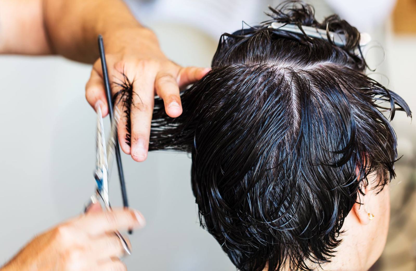 Professional hairdresser cutting blonde hair with scissors in a salon close-up.
