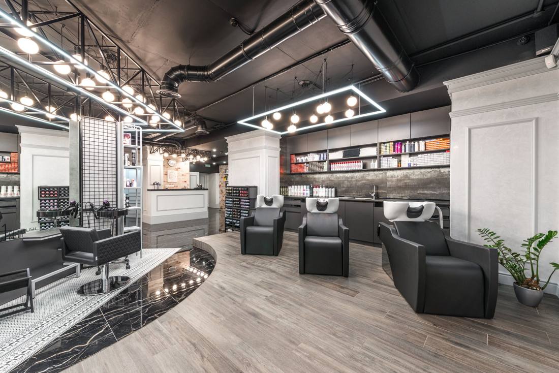 A female stylist expertly applying hair color to a client in a modern salon setting.